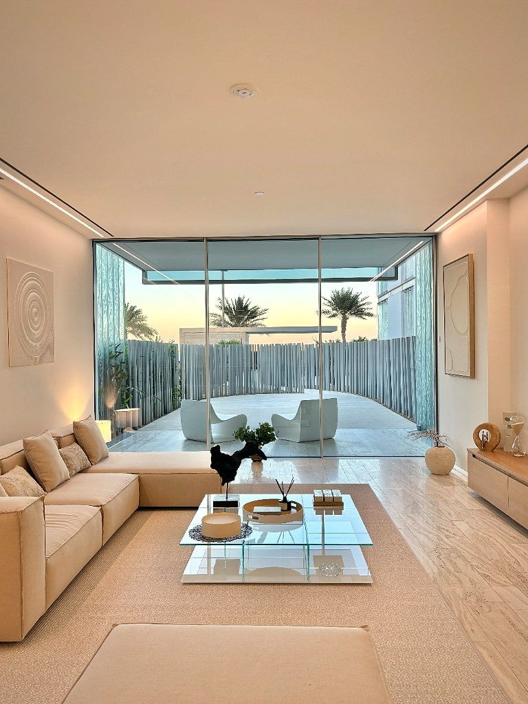 Twilight living room of a Palm Jumeirah apartment opening to a fluted-stone terrace