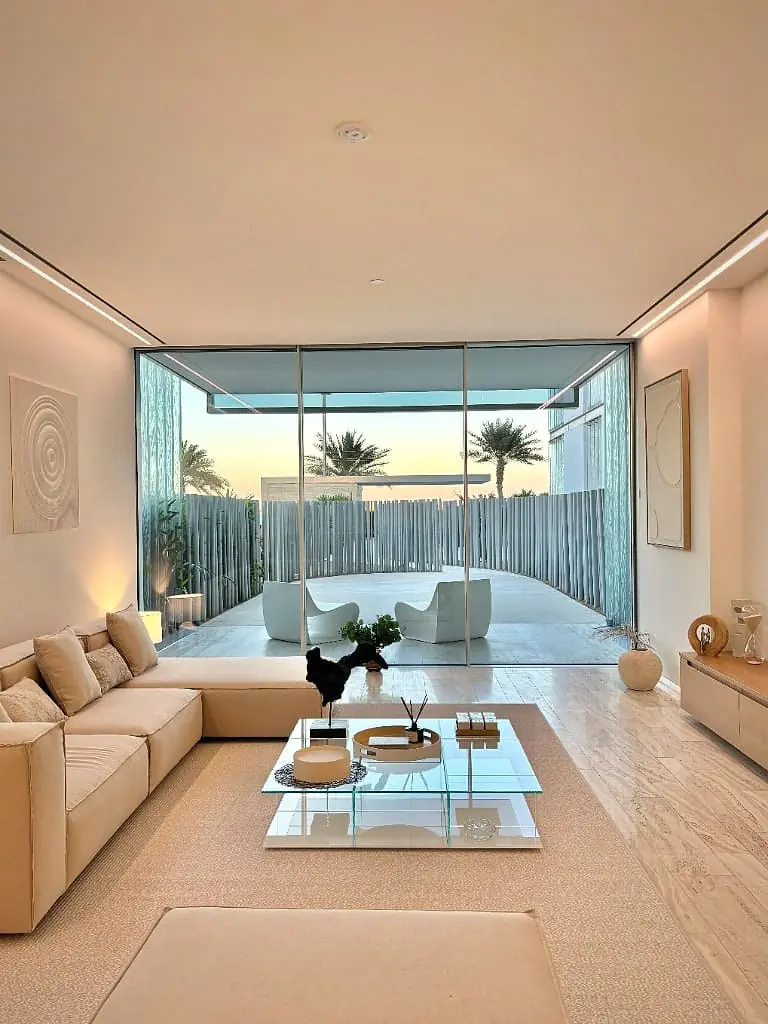 Twilight living room of a Palm Jumeirah apartment opening to a fluted-stone terrace